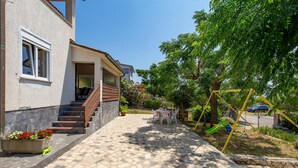 A house with a paved entrance, a staircase, and a garden area with a swing set. - Beach front home in Barbat na Rabu (Barbat na Rabu)