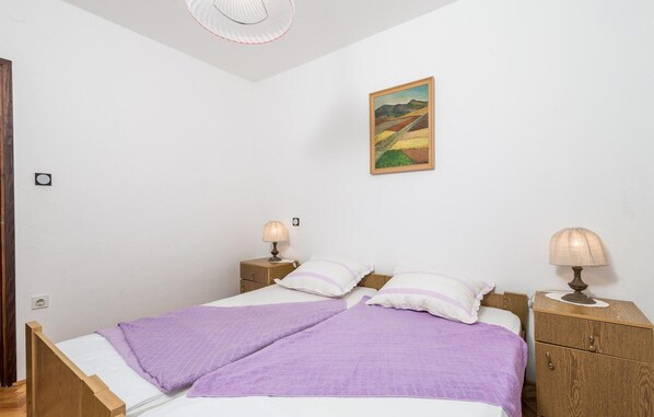 Un dormitori amb un llit, dues taules de nit, una làmpada, un quadre i un ventilador de sostre.
