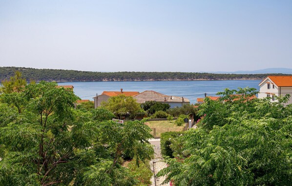 A coastal village with houses, a clear view of the sea, and lush greenery.
