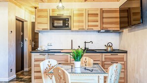 A modern kitchen with wooden cabinets, a stainless steel oven, a black countertop, and a dining table with chairs. - Beautiful apartment in Koscielisko with sauna (Koscielisko)