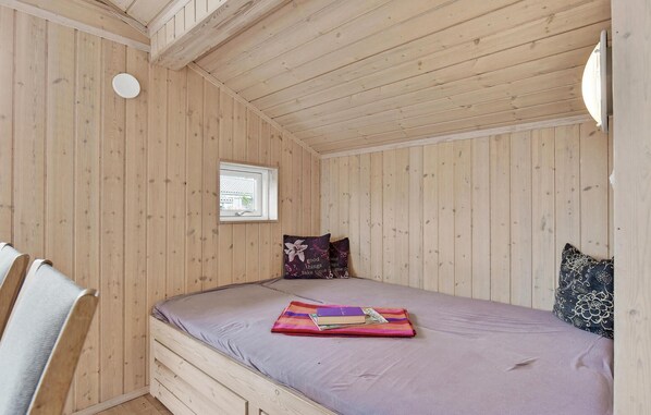 A small, wooden-paneled room with a single bed, a window, and a chair. - 3 bedroom awesome home in Juelsminde (Juelsminde)