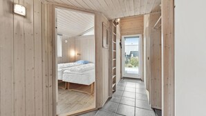 Interior em madeira com uma cama, uma janela pequena e vista para o exterior.