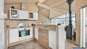 Cozinha moderna com armários brancos, forno Bosch e uma grande janela com vista para um jardim.