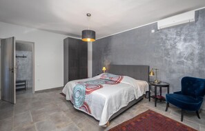 Ein modernes Schlafzimmer mit einem Bett, einem blauen Sessel, einer Lampe und einem Heizgerät.
