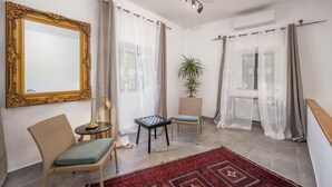 A room with a large ornate mirror, a chess table, wicker chairs, a potted plant, and a red patterned rug. - Amazing home in Tribalj (Tribalj)