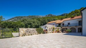 A villa with a stone wall, outdoor seating, and a view of mountains. - Amazing home in Tribalj (Tribalj)