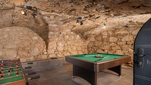 A billiards table in a room with stone walls and a foosball table. - Amazing home in Tribalj (Tribalj)