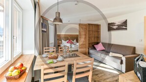 A modern living room with a wooden dining table, chairs, a sofa, and a TV. - schoene Ferienwohnung (Klösterle)