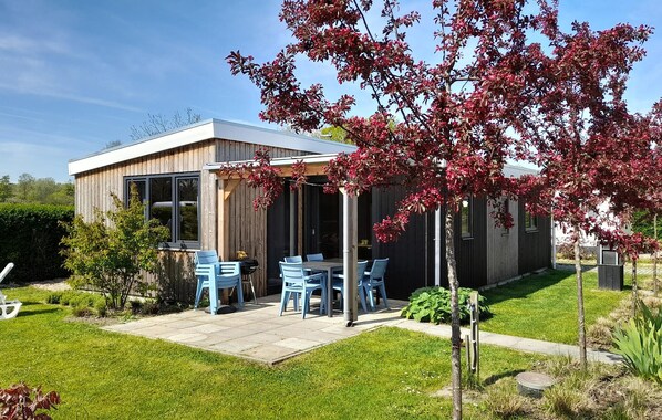 A modern house with a patio, outdoor seating, and a garden.