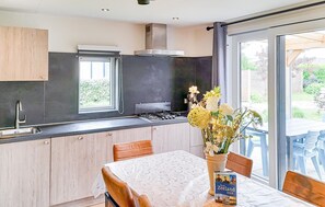 A modern kitchen with a gas stove, a window, and a dining area with a table and chairs.