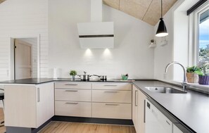 Enjoy cooking in this well-equipped kitchen with a central island, oven, and stainless steel sink.