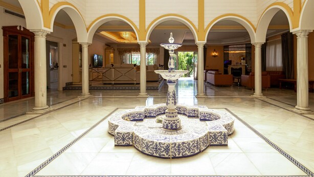A spacious lobby with a central fountain, arched columns, and a fireplace in the background. - Beautiful home in Mijas Costa with sauna (Mijas Costa)