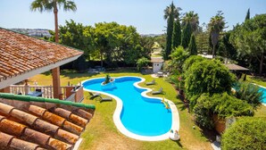 A swimming pool surrounded by lush greenery and a tiled roof structure. - Beautiful home in Mijas Costa with sauna (Mijas Costa)