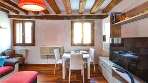 A dining area with a table and chairs, a television, and wooden beams on the ceiling. - Lovely apartment in Venezia with WiFi (Venezia)