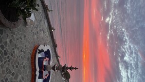 Une vue sur le coucher de soleil depuis une terrasse agrémentée d’une fontaine et d’un espace salon.