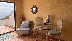 Un coin salon confortable avec une table en verre, des chaises en osier et un banc rembourré.
