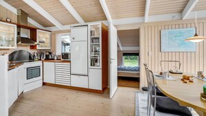 A modern kitchen with white cabinetry, a built-in oven, and a dining area with a wooden table and chairs.