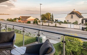 Enjoy the serene view of the body of water from this balcony, featuring comfortable wicker furniture.