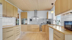 Una cocina moderna con gabinetes de madera, una campana extractora de acero inoxidable y un lavavajillas integrado.