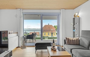 Relax in this stylish living room with a balcony offering views of a house and water.