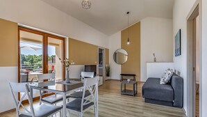 A modern living room with a dining area, a gray sofa, and a round mirror on the wall. - Lovely home in Barbariga (Barbariga)