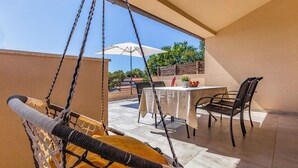 A balcony with a hanging chair, a table with chairs, and a white umbrella. - Lovely home in Barbariga (Barbariga)
