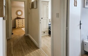 Un pasillo que conduce a un dormitorio con cama y cómoda.