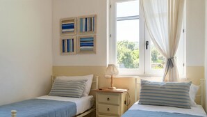A bedroom with two single beds, a nightstand, a lamp, and a window with curtains. - 2 bedroom pet friendly apartment in Sorso (Sorso)