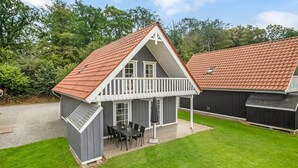 A two-story house with a red-tiled roof, a balcony, and a small outdoor dining area with a table and chairs. - Cozy home in Gråsten with kitchen (Gråsten)