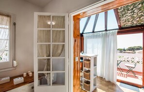Une pièce dotée d’une grande fenêtre, d’une porte en bois et donnant sur un balcon aménagé avec du mobilier d’extérieur.