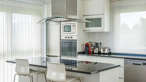 A modern kitchen with a central island, a built-in oven, and a coffee maker. - Gorgeous home in Noia (Noia)