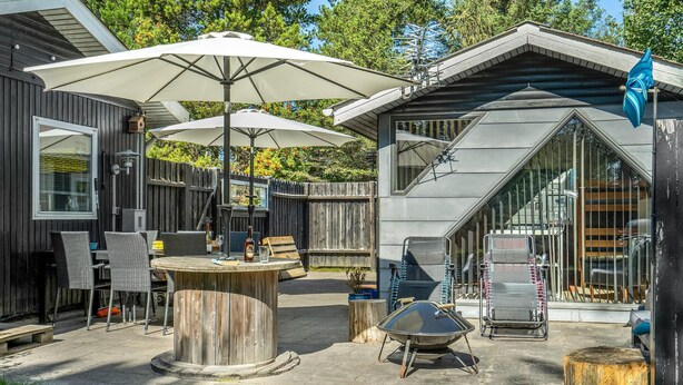 Un espace patio aménagé avec du mobilier d’extérieur, notamment une table et des chaises, ainsi que deux grands parasols pour créer de l’ombre.