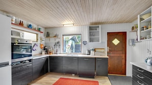 Une cuisine moderne avec des meubles de couleur sombre, un plafond en bois et un tapis rouge.