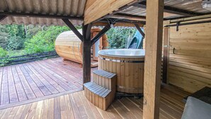 Una terraza de madera con un jacuzzi y escalones de madera que lo conectan.