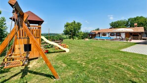 Eine hölzerne Spielanlage mit Rutsche, einem kleinen Tisch und einer Bank im grünen Rasen.