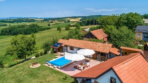 Ein Haus mit Swimmingpool, Gartenmöbeln und Blick auf die umliegende Landschaft.