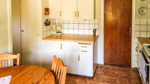 Eine kleine Küche mit weißen Schränken, einer Holz Arbeitsplatte und einer Kaffeemaschine.