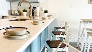 Een moderne keuken met een centraal eiland, een paar barstoelen en een broodrooster.