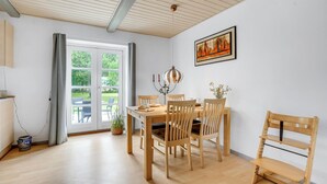 Zona pranzo con tavolo e sedie in legno, un lampadario e un quadro appeso al muro.