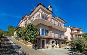 Classic two-story residence with a traditional stone archway entrance, featuring a balcony for outdoor relaxation and a patio area with seating.
