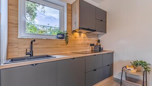 Une cuisine moderne dotée d’un évier encastré, d’un plan de travail en bois et d’une fenêtre donnant sur un espace verdoyant.