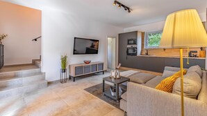 Un salon moderne avec un téléviseur à écran plat, un canapé, une table basse et une lampe.