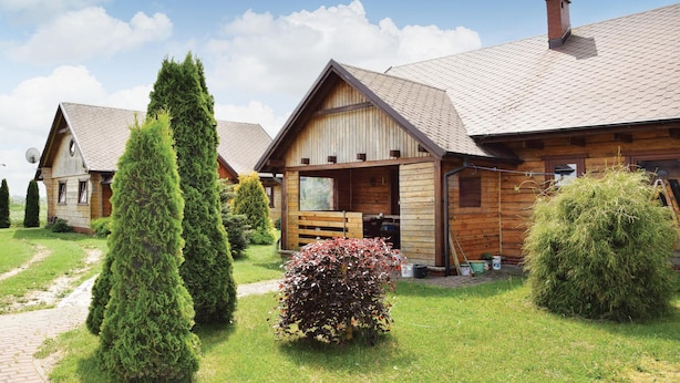 Eine Reihe aus Holzbungalows mit einem gepflasterten Weg und ordentlich geschnittenen Büschen.