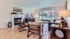 Ein geräumiges Wohnzimmer mit Kamin, Essbereich und großem Fenster mit Blick auf einen Garten.