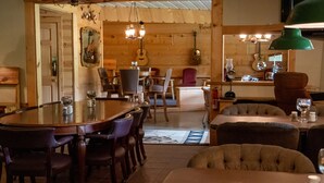 Un comedor con mesa y sillas de madera, una zona de bar y una pared decorada con guitarras.