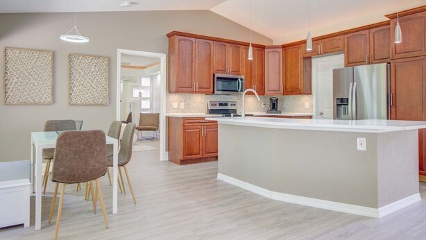 A modern kitchen with wooden cabinets, a central island, and pendant lighting.