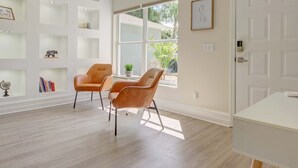 A spacious room with a large window, a white door, and a bookshelf with various items.