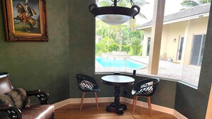 Una habitación con suelo de madera, un sofá de cuero marrón, dos sillas negras, una mesa redonda y un cuadro en la pared.