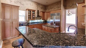 Una cocina amplia con encimeras de granito, armarios de madera y electrodomésticos de acero inoxidable.