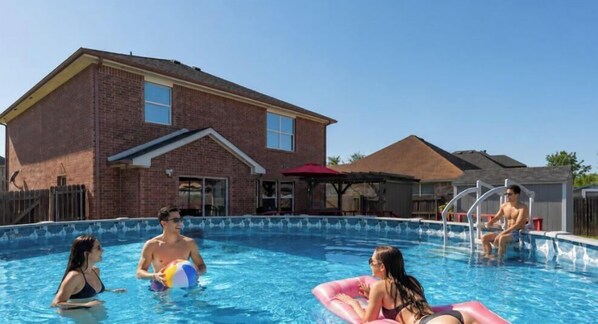 Una piscina con una casa in mattoni sullo sfondo.